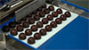 Maschine zum automatischen Ausformen von Pralinen und Schokoladentafeln